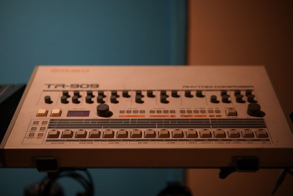 Photo by Giuseppe Di Maria Close-up of a classic Roland TR-909 drum machine in a studio setting.