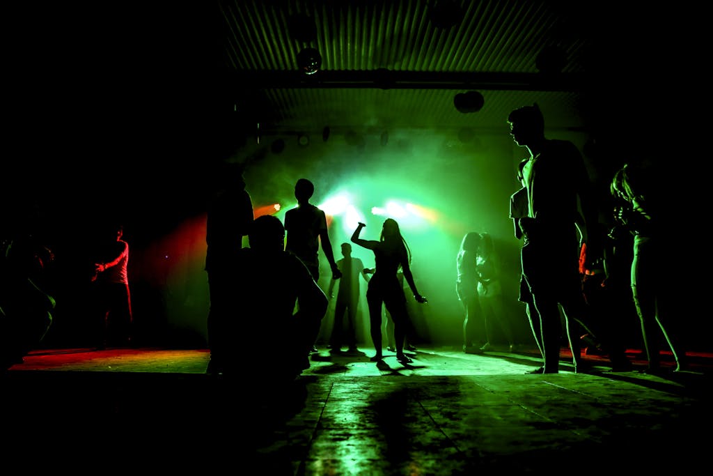 Photo by Maor Attias People dancing in a nightclub with colorful green lighting and vibrant atmosphere.